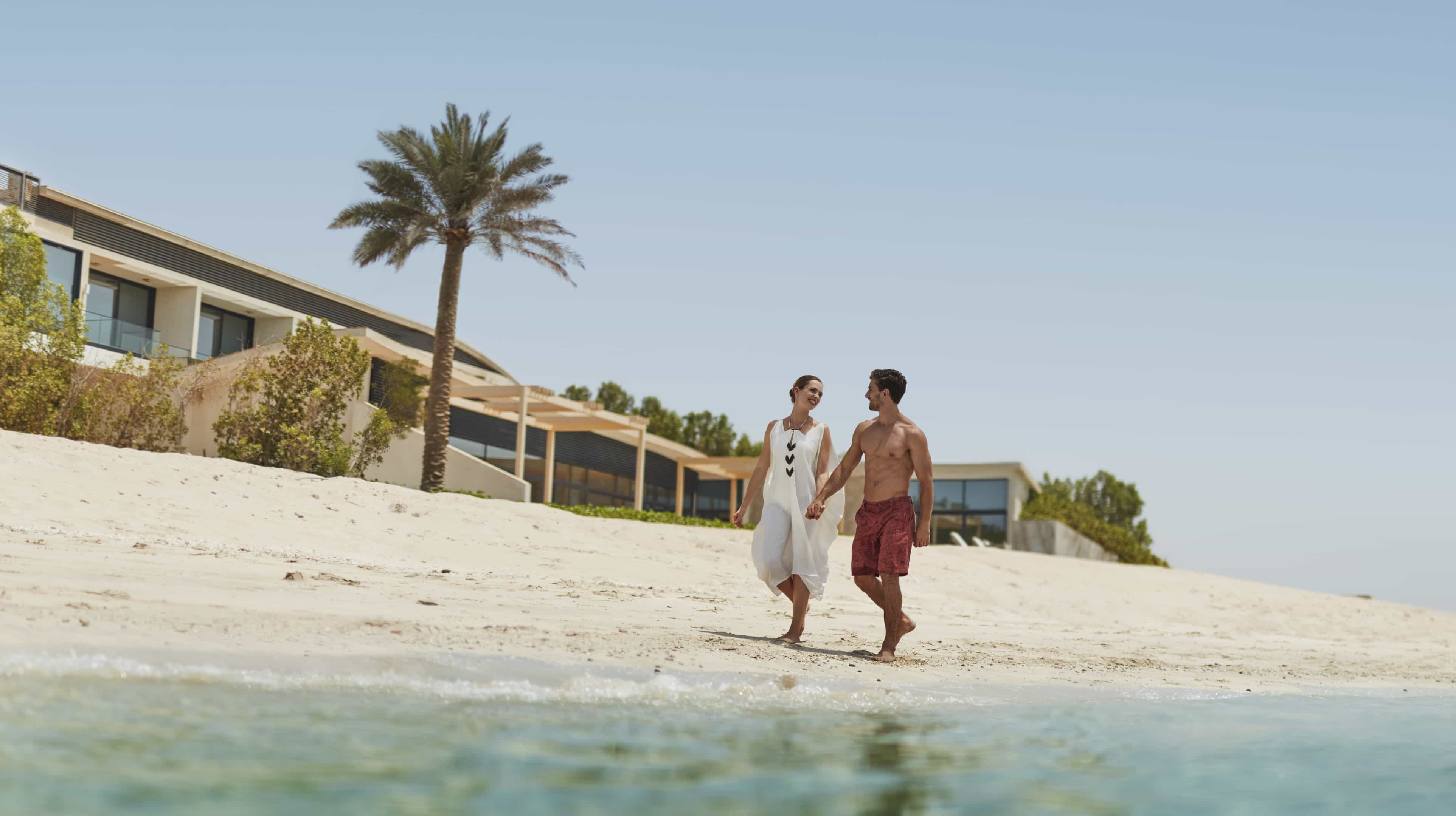زوجان أجنبيان يتجولان على شاطئ البحر في جزيرة نوراي