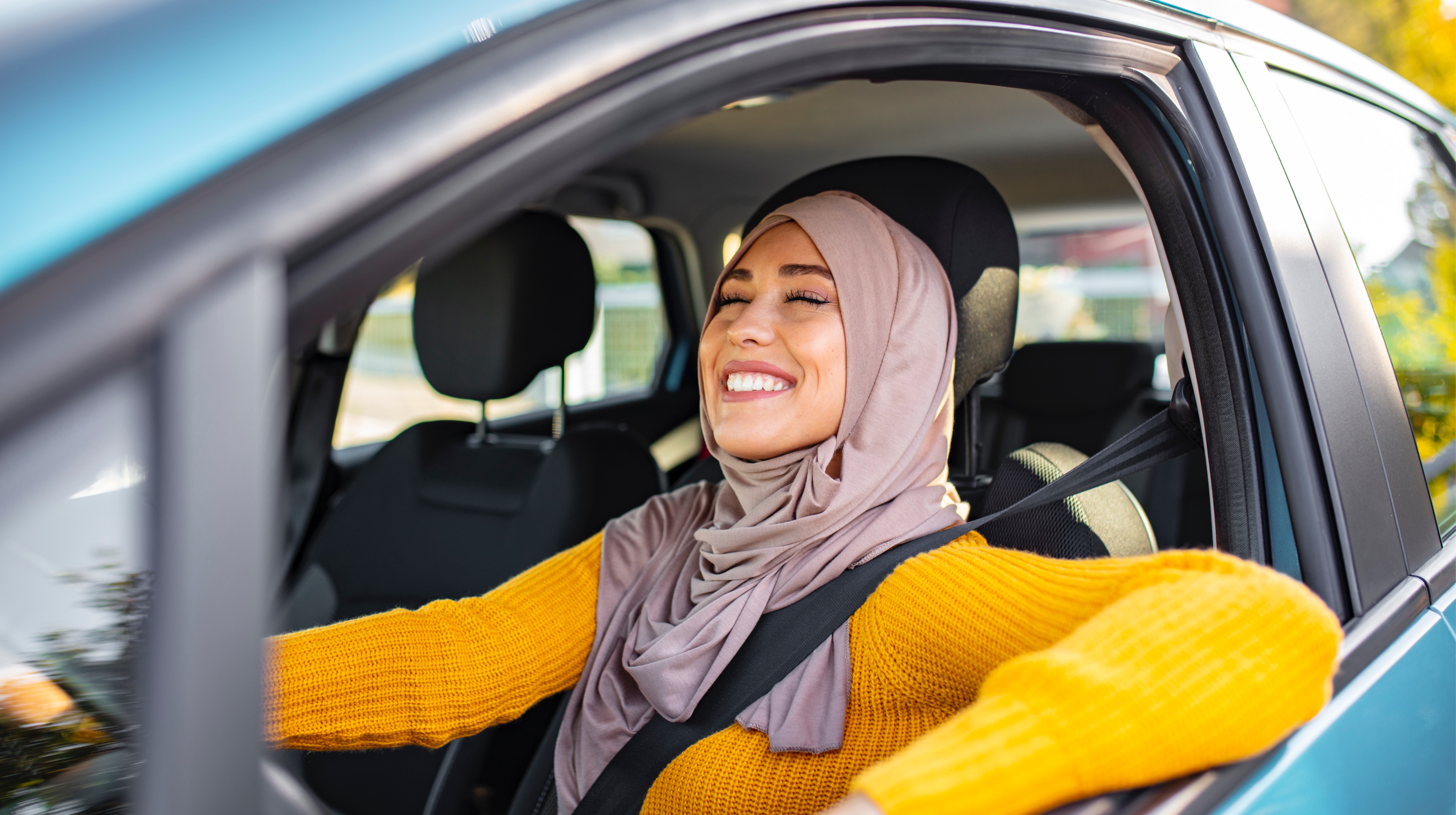 امرأة جميلة ترتدي الحجاب وتقوم بقيادة سيارتها في أنحاء إمارة أبوظبي