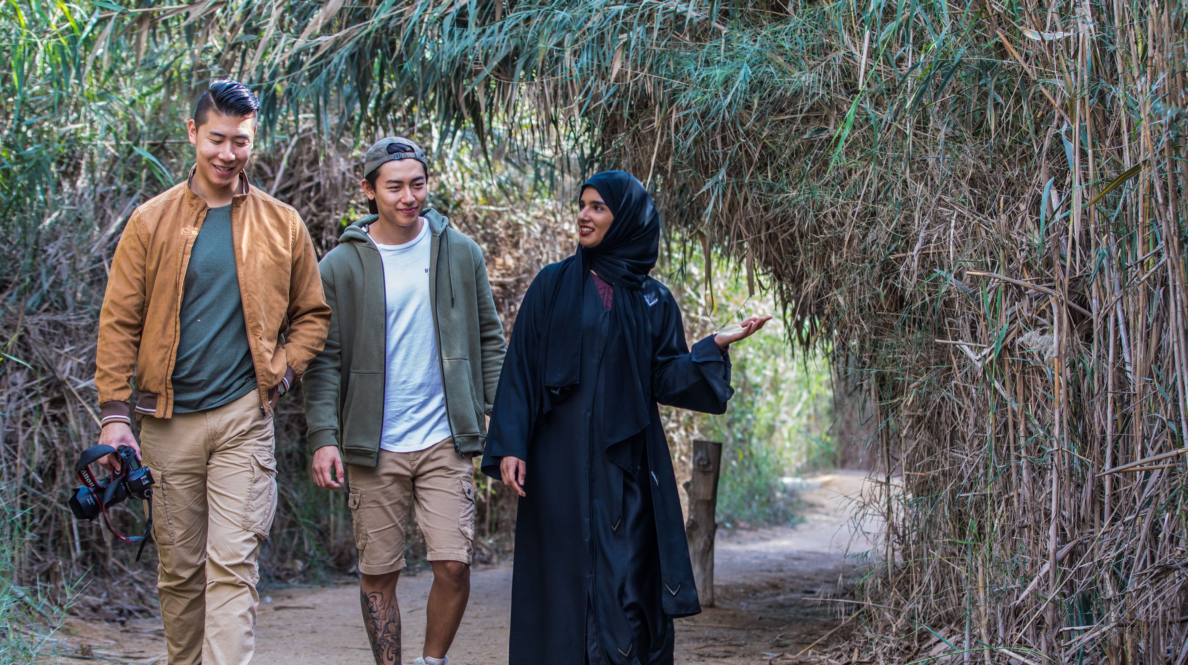 A female Emirati tourist guide with two Asian men amidst the nature in Abu Dhabi Emirate