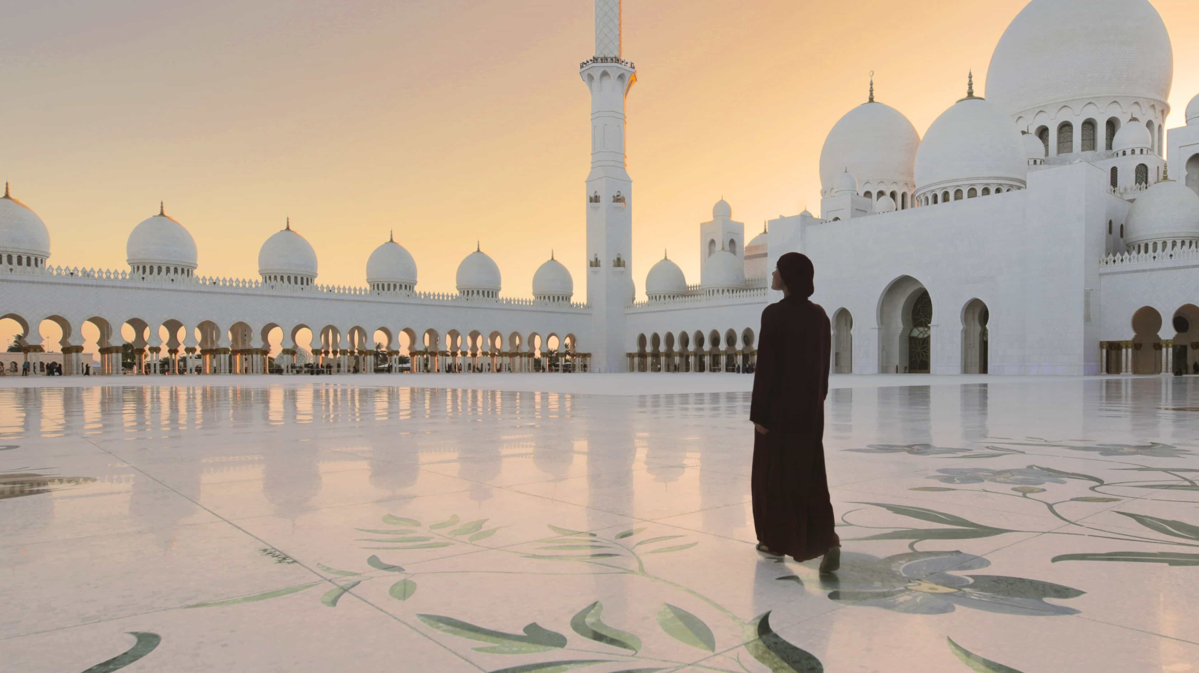 Hommes priant dans la célèbre mosquée d'Abu Dhabi, symbole de l'architecture de style arabe et de la spiritualité.