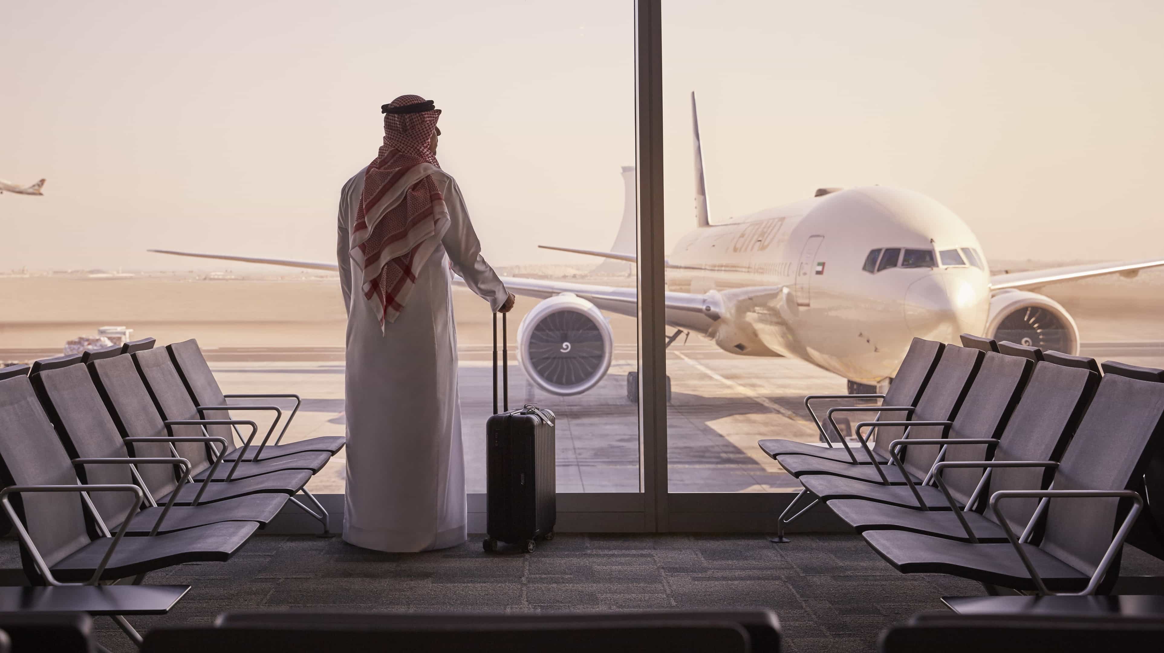 Арабский мужчина смотрит на самолет в аэропорту Абу-Даби