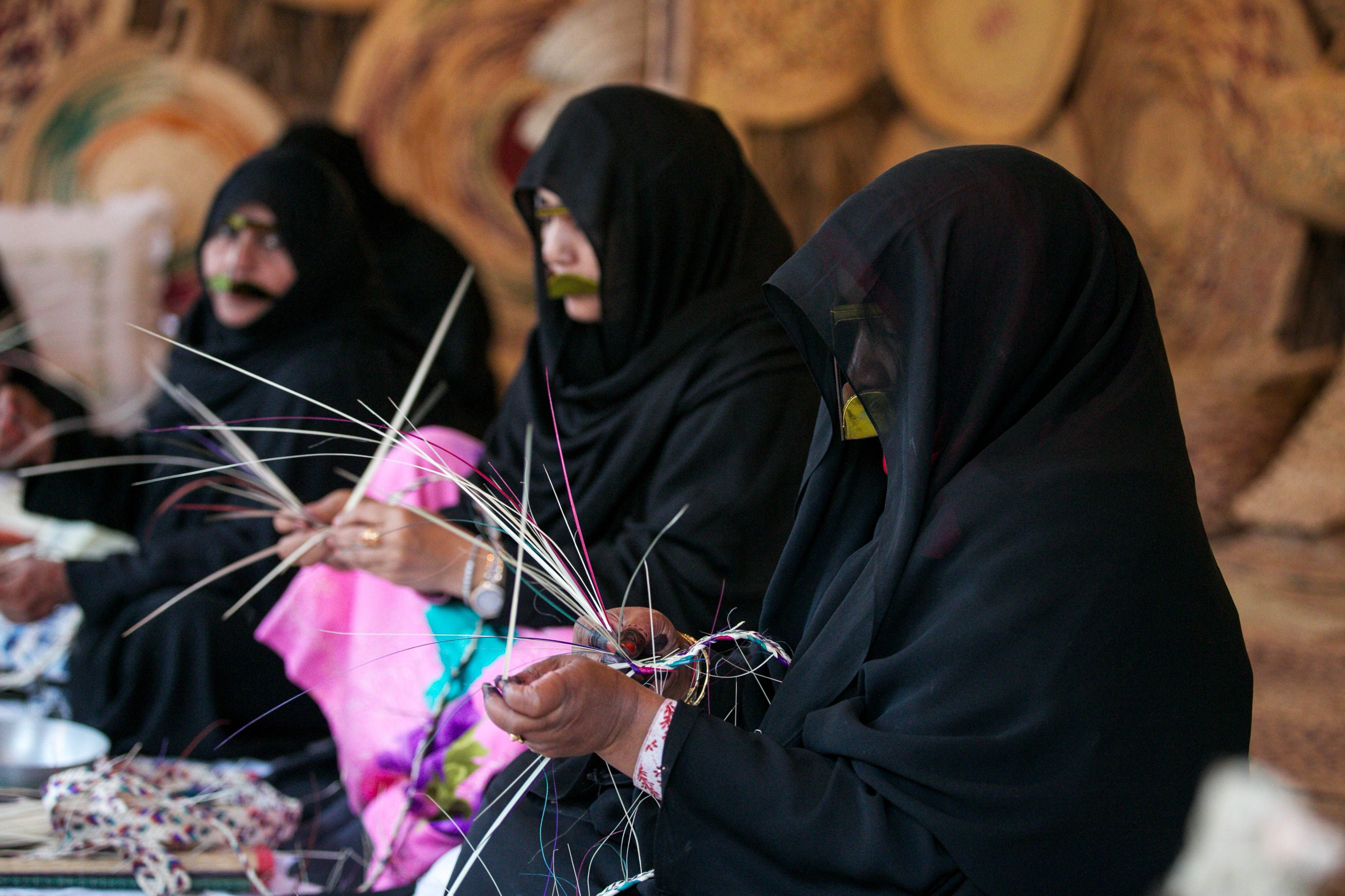 Three Emirati women making traditional handicrafts at House of Artisans