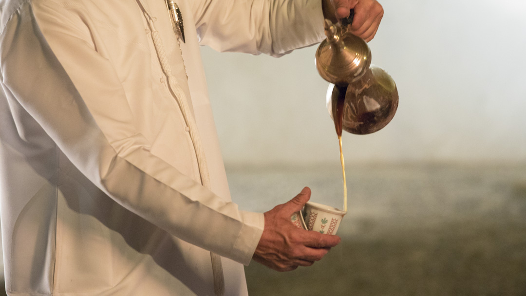 Emirati man's hand pouring traditional Arabic coffee at Qasr Al Hosn