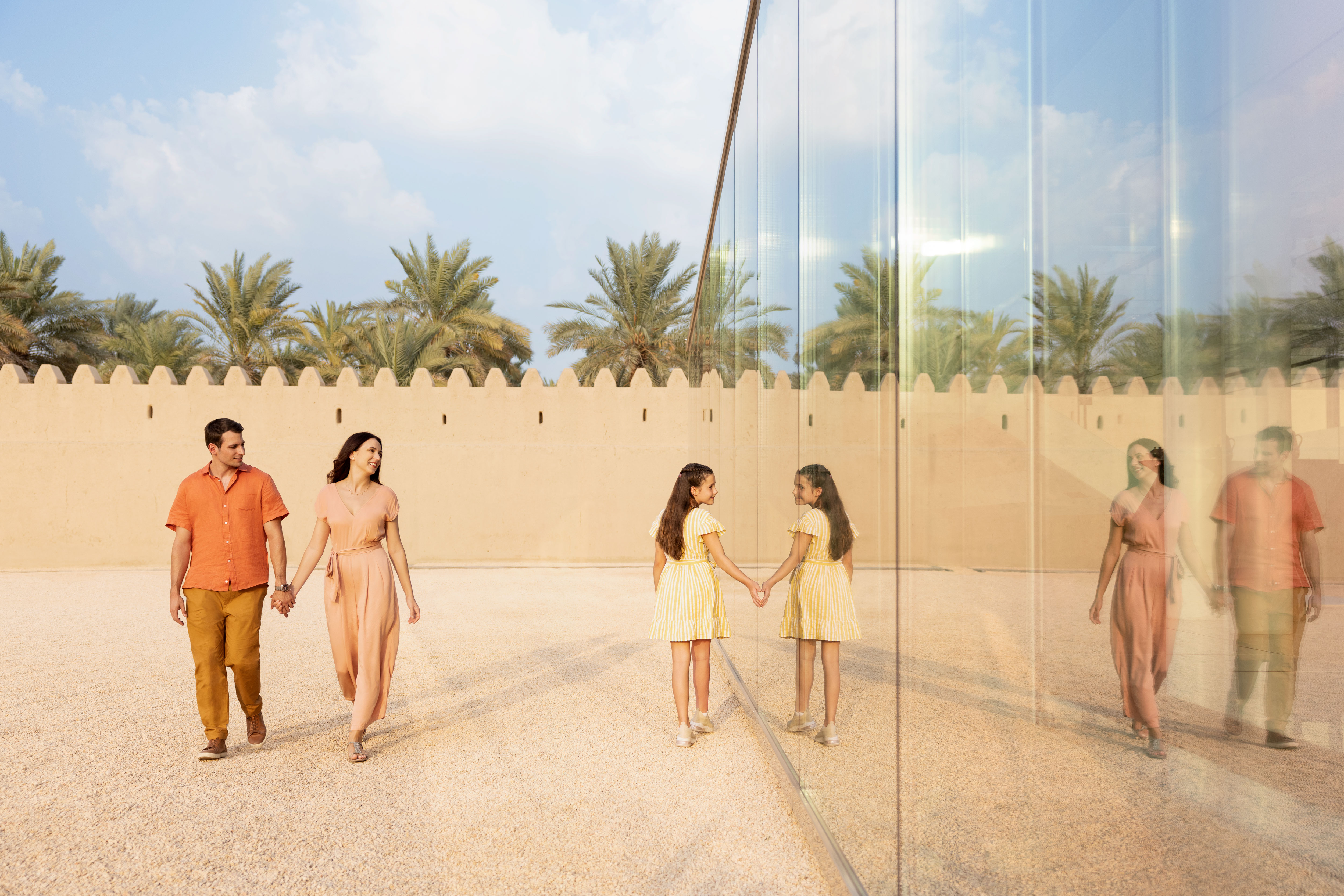 Un uomo, una donna e sua figlia sono di fronte a una parete a specchio in Abu Dhabi.